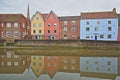 The riverside river Wensum with reflections of colorful houses and the tower and spire of the Cathedral