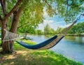 A riverside view with a hammock swaying gently in the breeze under shady trees