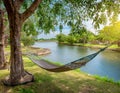 A riverside view with a hammock swaying gently in the breeze under shady trees