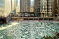 Riverwalk alongside ice chunk covered, frozen Chicago River is aqua blue and runs through Chicago Loop