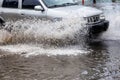 Ãâriving car on flooded road during flood caused by torrential rains. Cars float on water, flooding streets. Splash on car.