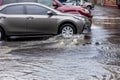 Ãâriving car on flooded road during flood caused by torrential rains. Cars float on water, flooding streets. Splash on car.