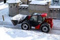 RIVNE, UKRAINE - FABRUARY 16, 2021. Removing snow from the streets with a tractor. A bulldozer with a bucket clears snow from the