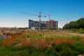 RIVNE, UKRAINE - JUNE 16, 2023. Construction of a building on the outskirts of the city. Field of green grass with blooming red