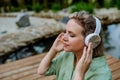 Rlaxed woman wearing headphones listening to music sitting on a pier by natureal lake in summer Royalty Free Stock Photo