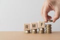 RMF for Retirement Mutual Fund, RMF word on wooden cube block on stack of coin with hand arranging coins. For saving