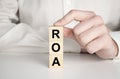 roa - return on assets acronym, wooden blocks, business concept gray background, financial document