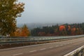 The road across the Jihlava river at the Dalesice water reservoir. Colorful trees in autumn fog