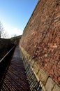 Road along the baroque bastion. modern railing made of corten sheet metal. The sidewalk is paved with burnt bricks. the high wall