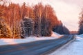 A road amid the snow-covered winter forest on a frosty morning. The morning dawn sun falls on the snow covered trees Royalty Free Stock Photo