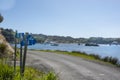 Road around coast or waterfront of Half Moon Bay with typically island posts with street numbers in white lettering on blue