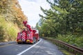 Road assistant helper bright red big rig tow semi truck with towing equipment running on the winding narrow mountain road