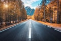 Road in autumn forest at sunset in Italy. Mountain roadway