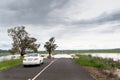 Road blocked by deep floodwater runoff from a field car unable to pass