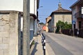 Road bordered by houses with a church at the end of it on a sunny day in a village in the italian countryside