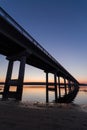 Road bridge over the river at dusk, view from below. Suburban architecture