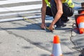 A road builder on the asphalt makes the markings of a pedestrian crossing on a summer day