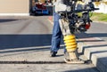 A road builder uses a vibration rammer to repair an asphalt road section