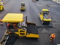 Road-building machinery and workers conduct asphalt work in the parking lot at the shopping center under construction in the fall