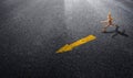 Wooden model running follow yellow arrow traffic signs on asphalt road.