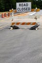 Road Closed sign on a battered traffic barricade, safety barrels and roadway construction, creative copy space