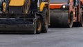 Road construction machinery performs work on laying asphalt on the road in close-up Royalty Free Stock Photo