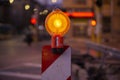 Road construction sign light in orange on a red and white stand Royalty Free Stock Photo