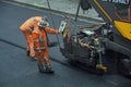 Road construction workers working with road paving machine