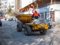 Road construction worker driving between parking cars on the narrow street. Royalty Free Stock Photo