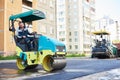 Road construction. Worker on steam vibration roller compacting asphalt Royalty Free Stock Photo