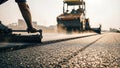 Road construction worker using a leveling tool on freshly laid asphalt, with heavy machinery in the background, showcasing the Royalty Free Stock Photo