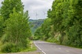 Road in the countryside surrounded with trees and big wind turbines in the background Royalty Free Stock Photo