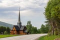 Road curving towards Kvikne kirke, a traditional Norwegian wooden church with a tall spire