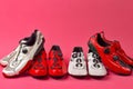 Road Cycling Concepts. Four Pairs of Carbon Red and White Professional Cycling Shoes Placed Together in Line Over Pink Coral