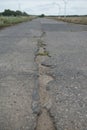 A road damaged by rain and snow, that is in need of maintenance. Broken asphalt pavement resulting in a pothole, dangerous to