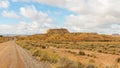 Road at a desert with a view of a monolith under a cloudy sky