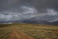Road dirt steppe rainbow mountains clouds Royalty Free Stock Photo