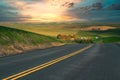 Road with dividing line in the countryside with colorful sunset in the distance