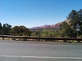 Road facing trees and vivid red and orange mountains