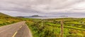 Empty road leading to village, coastline and islands in a distance, moody dark sky with stormy clouds Royalty Free Stock Photo