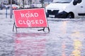 Road flood closed sign under deep water during bad extreme heavy rain storm weather in UK Royalty Free Stock Photo