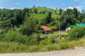 The road at the foot of the green mountain slopes with small rural houses and yards Royalty Free Stock Photo