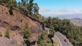 Road through the forest with tall trees, serpentine in the mountains of Tenerife, Spain. Car move along a ridge, aerial Royalty Free Stock Photo