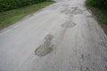 The road is full of holes and potholes. The old asphalt road surface is rough and bumpy and in need of repair.