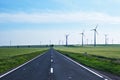 Road going forward with wind turbines on its sides and into the distance, on blue skies. Concept for sustainable energy solutions. Royalty Free Stock Photo