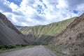 The road going to the colorful mountains and snow-capped peaks against the backdrop of a cloudy sky. Traveli Kyrgyzstan Royalty Free Stock Photo