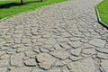 The road of gray stones against the background of green lawns in the city park. Place for walking