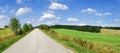 Road among green fields, blue sky and white clouds Royalty Free Stock Photo