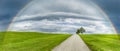 Road in a green hilly landscape with a rainbow