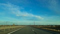 A road or highway leading to the horizon. View from the car window. Northern dim summer, blue sky with white clouds Royalty Free Stock Photo